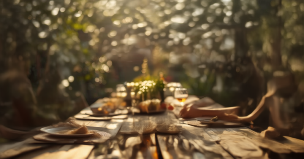 Table dressée en extérieur pour un anniversaire écoresponsable avec vaisselle et boissons consignées, ambiance conviviale au coucher du soleil